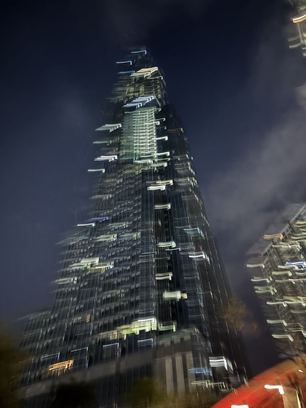 Skyscraper at night shot from below with blurred light trails