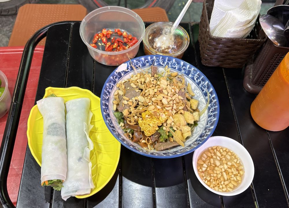 Street food tray with spring rolls and a noodle bowl topped with peanuts