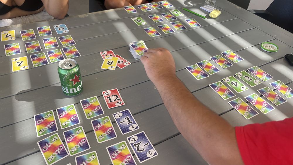 Colorful playing cards spread out on a table next to a green can